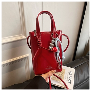 Detail of red patent leather bucket bag with heart metal charm and brand logo on bottom