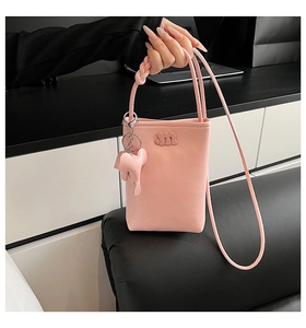 Detailed macro view of pink litchi grain faux leather phone bag with m logo and elephant charm