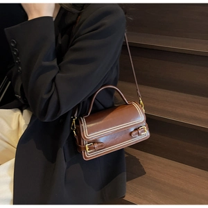 Detail of vintage brown leather handbag with pearl bead trim and gold buckles on a dark background