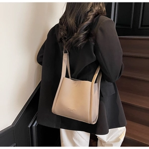 Detail of beige lychee pattern bucket bag with fashion leather embossing on shoulder
