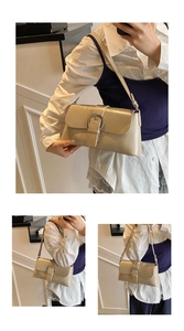 Detailed view of cream leather underarm bag featuring a metallic silver circular buckle detail