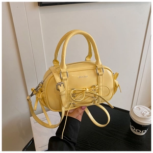 Detailed macro of a yellow patent leather Boston bag with a chic bow and lace-up details