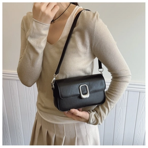 Chic black litchi pattern leather crossbody bag with silver buckle worn by a model