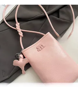 Close-up of pink leather phone bag featuring embossed m-logo and elephant charm detail