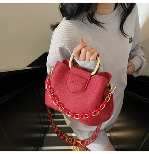 Detail of red lychee pattern leather bucket bag with gold handle and printed strap