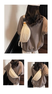 Detail of beige canvas crossbody bag showing metal buckle and brand label on strap