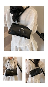 Close-up of black glossy shoulder bag featuring a silver horseshoe buckle detail