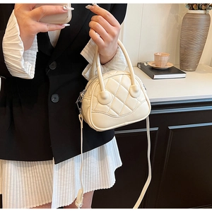 Detailed view of cream quilted Boston bag with textured PU leather and top handles