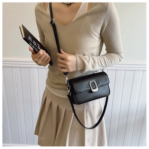 Detail of minimalist black crossbody bag with silver buckle worn by a model