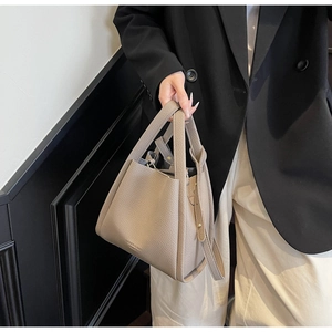 Detail of lychee pattern leather bucket bag showing dual handles and shoulder strap