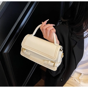 Detail view of cream white PU leather square bag with gold buckles and parallel stitching