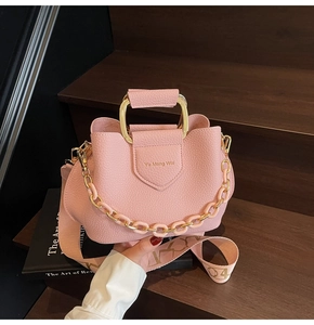 Detail of pink lychee leather bucket bag with gold metal handle and canvas strap