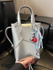 Metallic silver crossbody mini bag with heart charm and brand logo on a black background