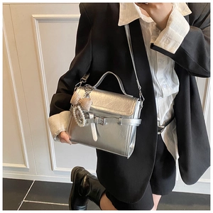 Detail of silver metallic handbag with pearl charm and checkered bow accessory