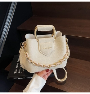 Close-up of litchi pattern leather bucket bag with gold handle and acrylic chain