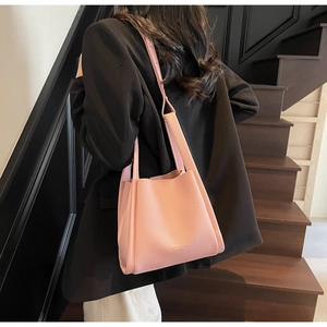 Rear view of a pink litchi leather handbag worn by a model in a black suit