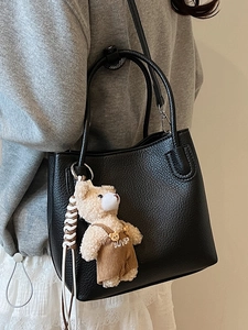 Chic black litchi pattern bucket bag with cute bear charm for elegant daily commuting