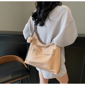 Detail of soft leather tote bag with side bear charm and adjustable strap shown on model