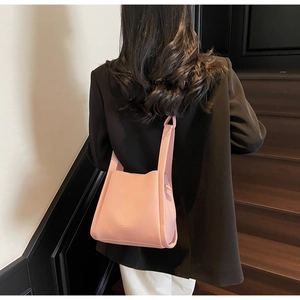 Pink lychee grain bucket bag worn by model with black blazer and white pants