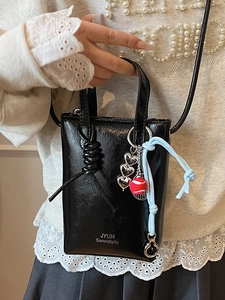 Chic black patent leather crossbody bag with heart charm and white branding for women