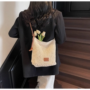 Détail du sac à bandoulière en crochet crème avec logo en cuir brun et cordons