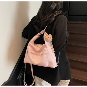 Pink faux leather tote bag detail with plush bear charm and metallic chain accessory
