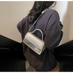 Detailed side view of silver metallic mini square bag with golden buckle and top handle