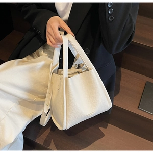 Detailed macro view of white lychee textured leather bucket bag with top handle and strap