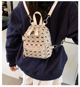 Detail of mini quilted backpack featuring black bow patterns and silver hardware accents