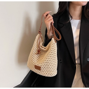 Détail du sac en maille crème avec texture tissée, bandoulière en cuir et perle en bois