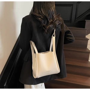 Detail view of white lychee textured leather bucket bag worn over the shoulder by a model