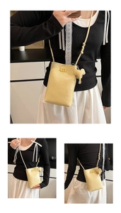 Detail view of yellow lychee texture leather crossbody bag with elephant charm
