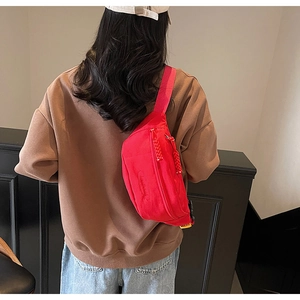 Close-up of bright red crossbody chest bag with adjustable strap and textured nylon finish