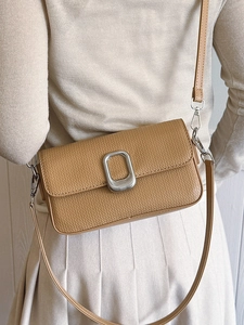Minimalist camel crossbody bag with wave texture and silver buckle worn by a model