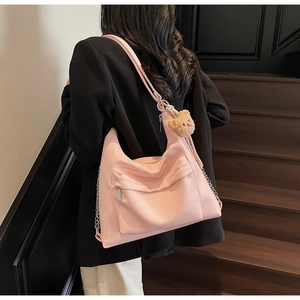 Pink faux leather tote bag detail with metal chain and plush bear charm on stairs