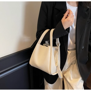 Detail of cream lychee texture leather tote bag held by model in minimalist fashion outfit