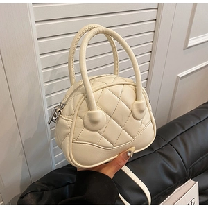 Detail of cream quilted crossbody shell bag showing leather texture and stitching