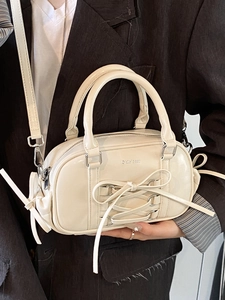Minimalist creamy white Boston handbag with elegant lace-up bow and leather shoulder strap