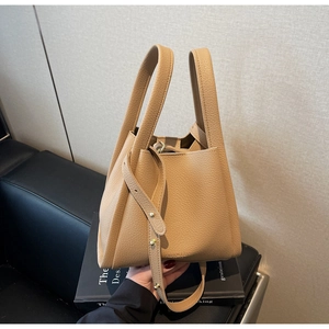 Detail of lychee pattern leather handbag featuring dual handles and a long shoulder strap