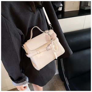 Chic beige crossbody square bag with pearl charm styled on a grey oversized blazer