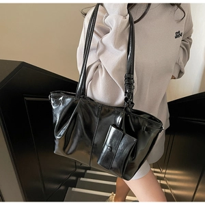 Détail du sac fourre-tout noir brillant en cuir ciré avec design plissé et petite pochette