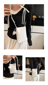 Close-up of white pebble leather crossbody phone bag with M-logo and cute elephant charm