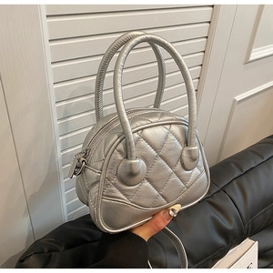Detail of silver quilted shell handbag featuring metallic finish and stitched textures