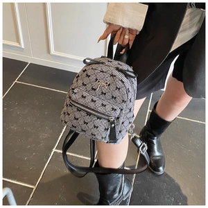 Detail of checkered mini backpack with golden bow hardware and faux leather trim