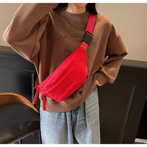 Detail of red canvas waist bag featuring oval embossed logo and red woven zipper pull