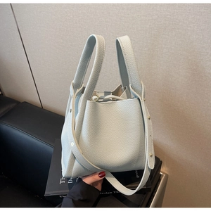 Detail of mint green lychee pattern leather bucket bag with gold rivet strap accents