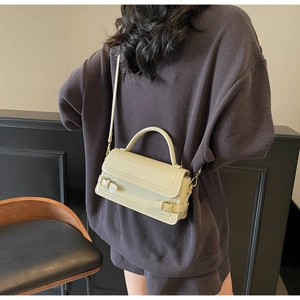 Detail of a beige vintage square crossbody bag featuring gold hardware and fine stitching