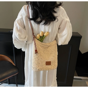 Détail du sac à bandoulière au crochet avec logo en cuir, pompons et décorations