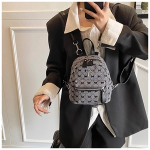 Detail of mini quilted backpack with black bows and metal clasp shown on a model