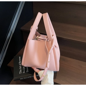 Detailed close-up of pink litchi grain texture and gold hardware on the bucket bag